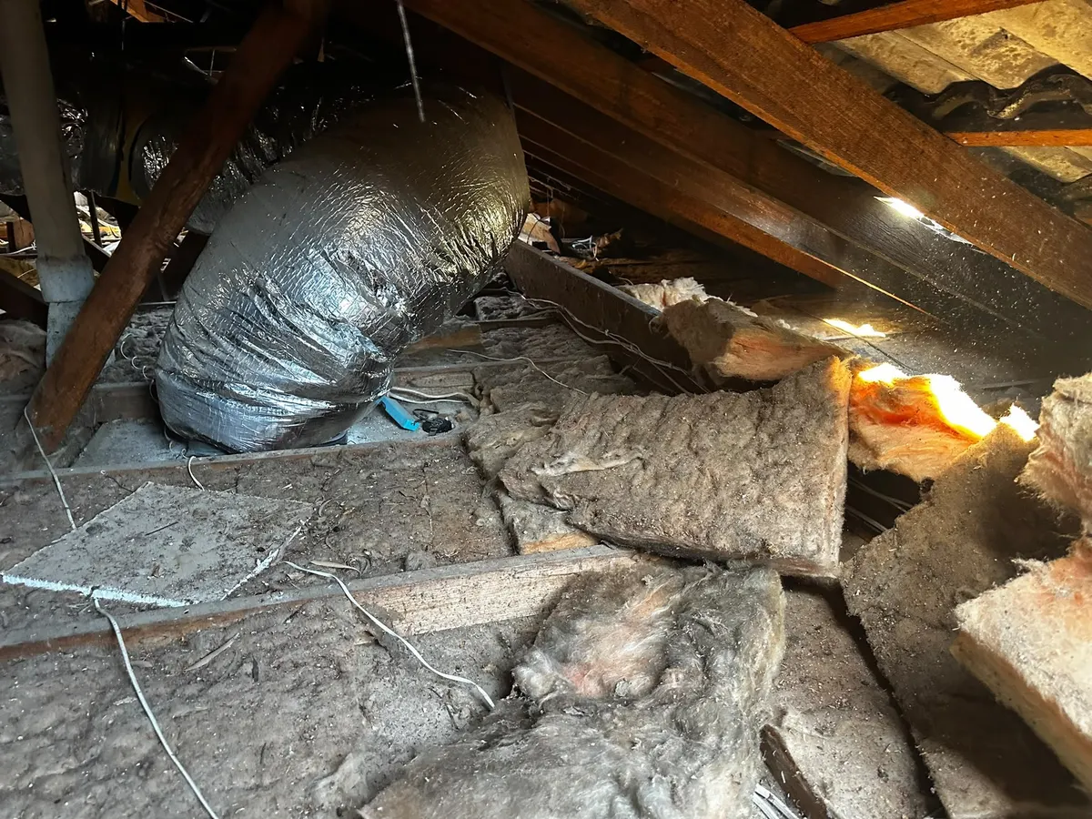 Roof cavity before removal, with old, dusty and torn insulation (photo 1 of 7)